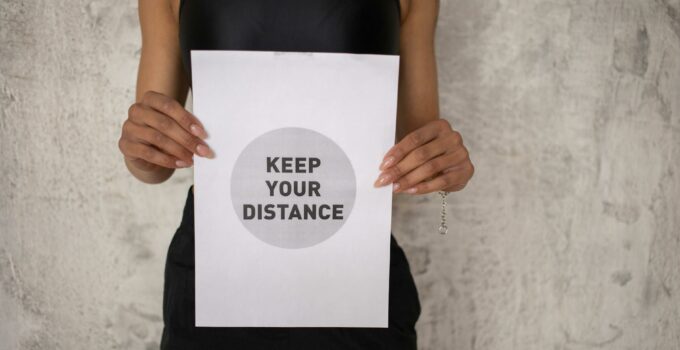 Black woman showing paper with inscription for keeping social distance