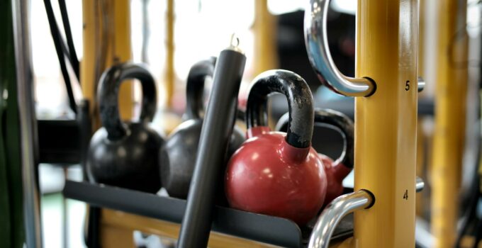 Set of different kettlebells placed in row on metal platform on modern fitness equipment in sport center