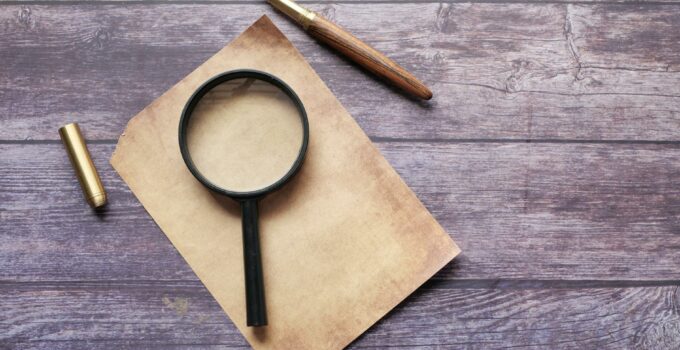 Magnifier and a Quill Pen on an Empty Paper Sheet