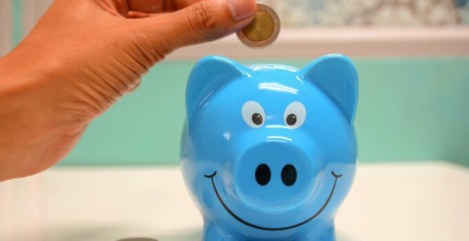 Person Putting Coin in a Piggy Bank