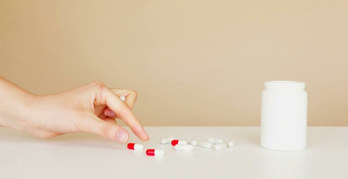 Crop patient taking pill from table