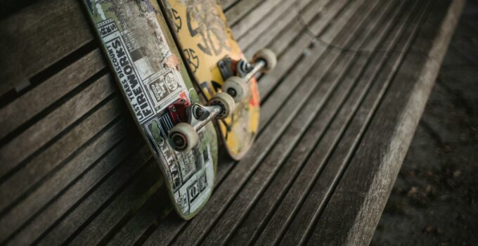 Boards with rollers for skateboarding placed on wooden bench in park in daylight