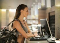 Fit smiling sportswoman waiting at gym reception desk