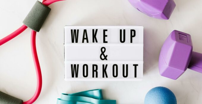 Wake up and workout title on light box surface surrounded by colorful sport equipment