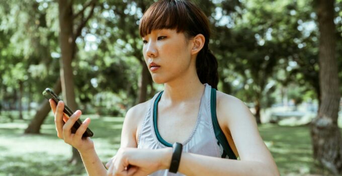 Concentrated young Asian woman using smartphone in park