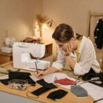 A Woman Drawing on a Paper while Making Face Mask Designs