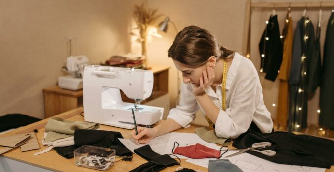 A Woman Drawing on a Paper while Making Face Mask Designs