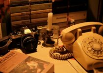 A desk with a telephone, books and a camera