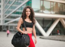 Selective Focus Photo of Smiling Woman In Active Wear Carrying Gym Bag