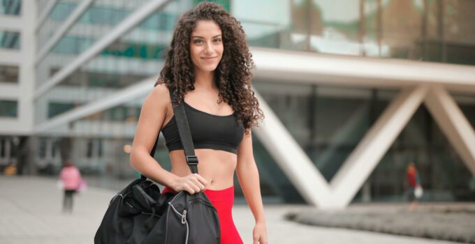 Selective Focus Photo of Smiling Woman In Active Wear Carrying Gym Bag