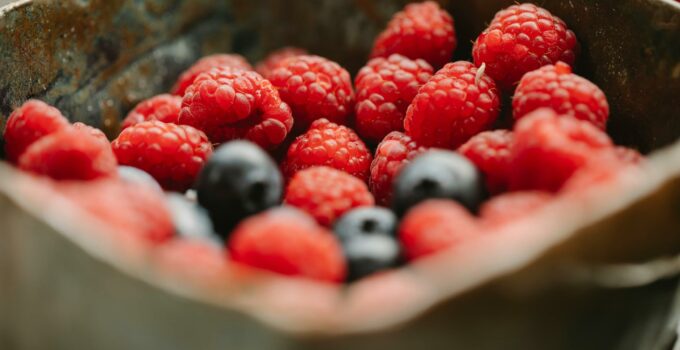 Appetizing ripe raspberries and blueberries in bowl