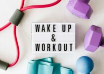 Wake up and workout title on light box surface surrounded by colorful sport equipment