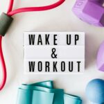 Wake up and workout title on light box surface surrounded by colorful sport equipment